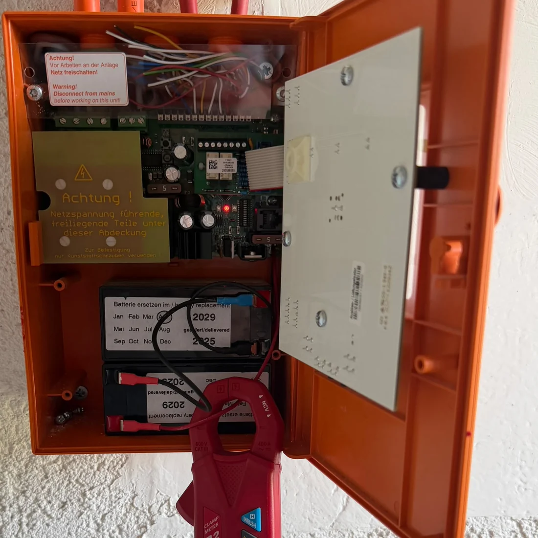 RWA-Zentrale geöffnet bei der Prüfung, Platine, Akkus und Zangenamperemeter